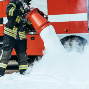 cropped shot of firefighter extinguishing fire with foam on street